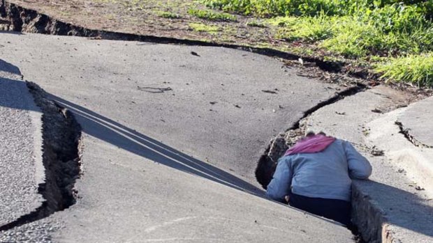 A child climbs into a ruptured Christchurch road.