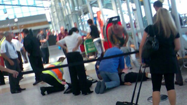 Bystanders with the victim of the attack at Sydney Airport's domestic terminal.
