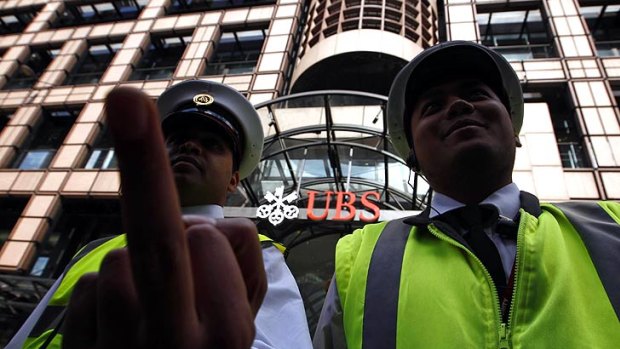 A security guard gestures as he stands with a colleague in front of a UBS bank in the City of London.