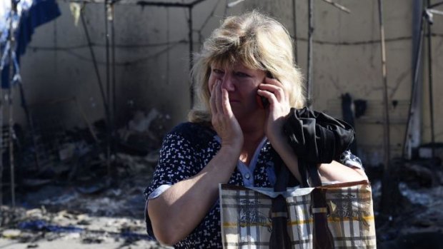 Irina, 42 years old, cries while giving a phone call in front of her destroyed shop, in a market gallery targeted by shelling, on Monday in the Kievsky district in Donetsk.