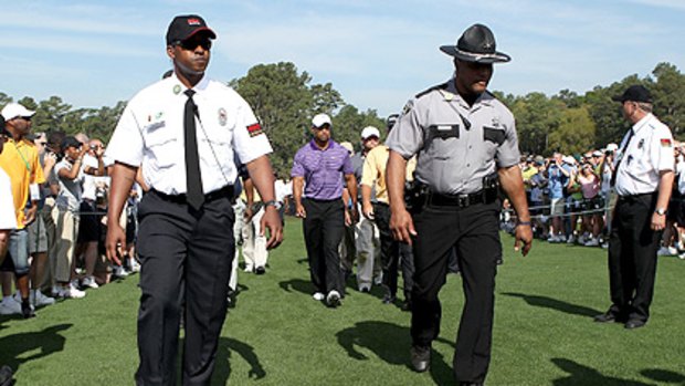 Tight security surrounds Woods as he plays a practice round at Augusta before his comeback tomorrow.