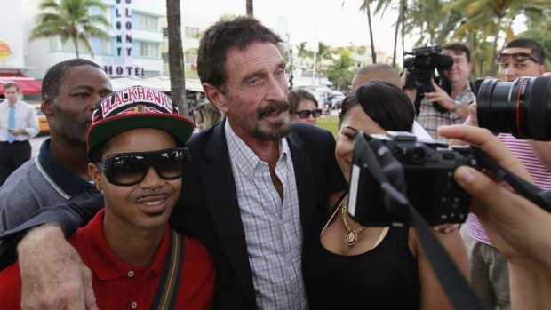 Computer software pioneer John McAfee, centre, poses with tourists as he speaks with reporters outside his hotel in Miami Beach, Florida.