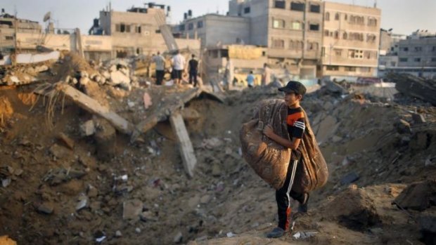 A Palestinian boy carries his belongings as he walks past the rubble of his family's house in Gaza City, which police said was destroyed in an Israeli air strike on Wednesday.