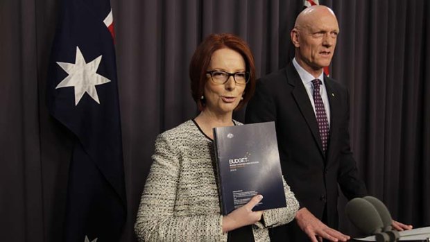 Prime Minister Julia Gillard refers to the 2013 Budget papers with school education minister Peter Garrett during a press conference at Parliament House Canberra on Sunday.