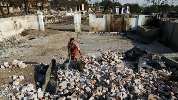 Grip of violence: A woman collects items from burnt Muslim homes in Meikhtila, central Myanmar, where neighbourhoods were razed in four days of violence in March that killed 43 people.