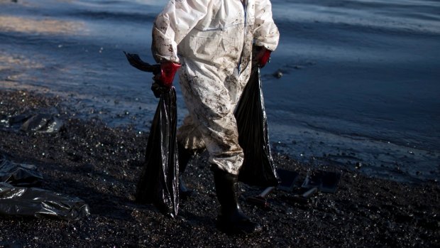 A worker carries fuel oil in bags as he cleans a polluted beach in the island of Salamina near Athens, on Friday.