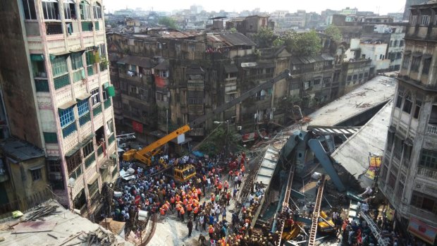 Locals and rescue workers clear the rubble of a partially collapsed overpass in Kolkata.