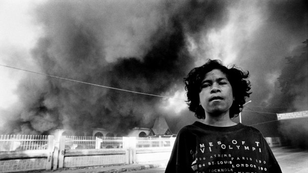 A young boy stands outside a burning government building. Departing Indonesian forces and local militias burn what's left of Dili's infrastructure. East Timor, September, 1999.