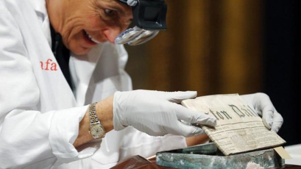 Conservator Pam Hatchfield removes a newspaper from a time capsule, which was placed under a cornerstone of the State House in 1795, at the Museum of Fine Arts, Boston, Massachusetts, January 6, 2015. The capsule was placed by a group of the U.S. founding fathers including Samuel Adams, then the state's governor, and patriot Paul Revere.