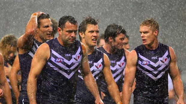 All at sea: Fremantle players head to the change rooms - and shelter from torrential rain - at half-time last night.