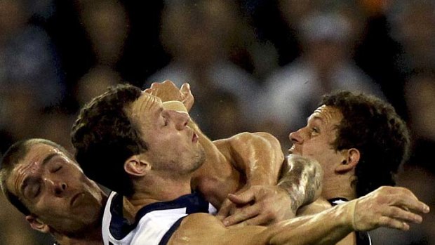 Strong-arm tactics: Geelong's James Kelly (middle) tackled.
