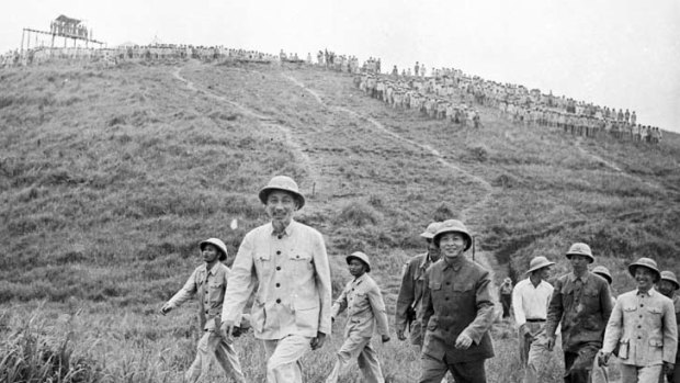Vietnamese President Ho Chi Minh strides ahead of General Giap on a visit to an army unit in 1957.
