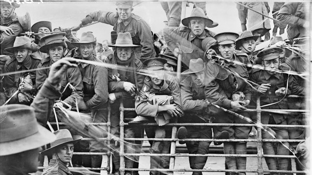 Troops on board HMAT Ajana (A31) prior to departure. A soldier (centre) is holding newspapers and books. Some are holding streamers thrown by well-wishers on shore. 