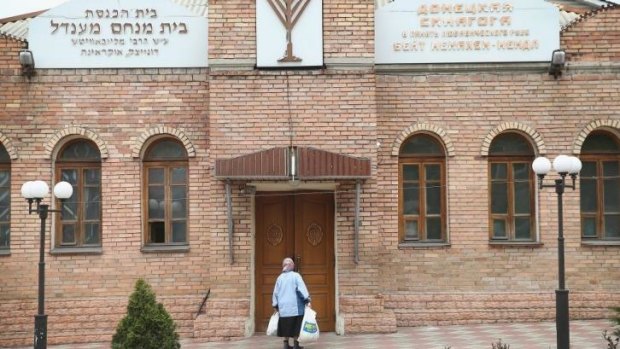 A woman stands outside the synagogue in Donetsk at the centre of the leaflet controversy.