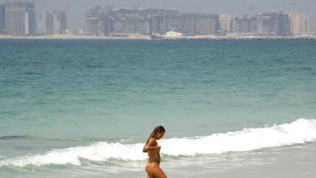 A swimmer walks on a beach in Jumeirah in Dubai.