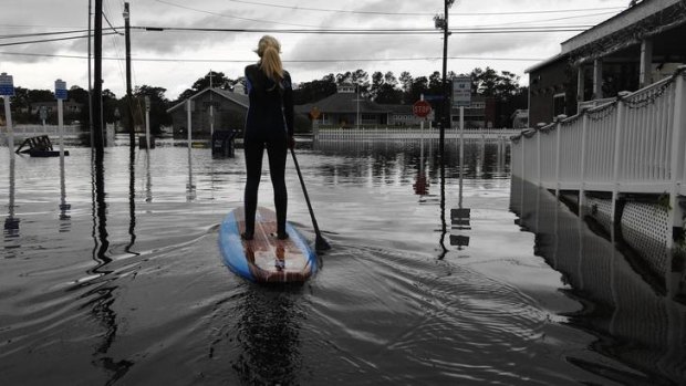 A woman paddle-boards down a flooded city street in the aftermath of Hurricane Sandy in Bethany Beach, Delaware.