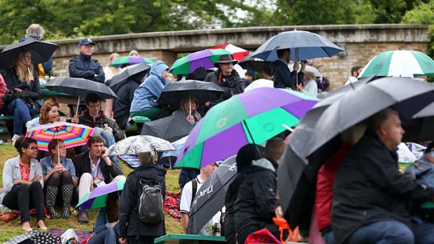 Sheltering from the rain on Murray Mount on day eleven of the Wimbledon Lawn Tennis Championships.