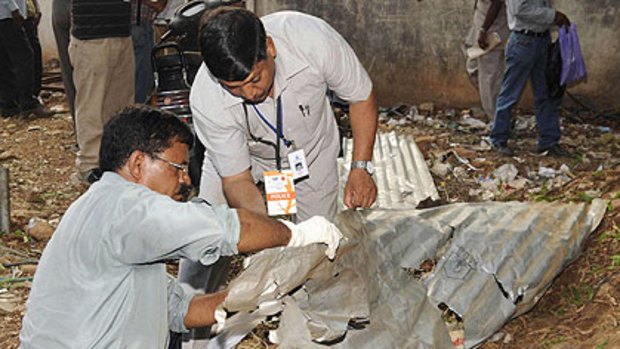 Forensic experts inspect the site of a bomb blast outside the Bangalore stadium.
