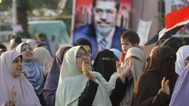 Supporters of Egypt's ousted President Mohammed Mursi shout slogans in front of his poster at a park in front of  Cairo University.