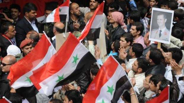 Supporters of Syrian President Bashar al-Assad wave flags at a rally in Damascus. 
