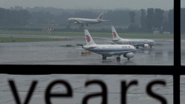 An Air China passenger plane lands while two other Air China planes wait to take off at Beijing International Airport.
