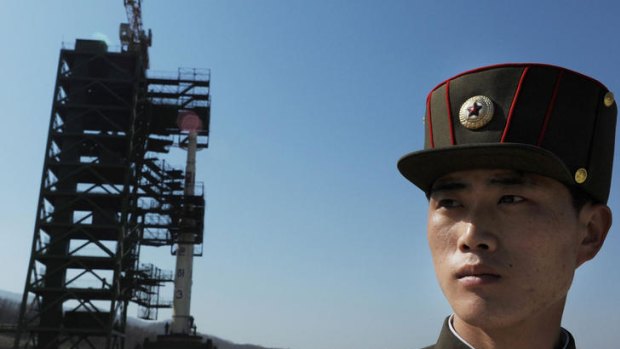 A North Korean soldier stands guard in front of an Unha-3 rocket at Tangachai-ri space centre.
