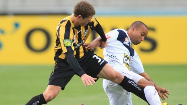 Wellington's Tony Lochhead tackles Melbourne Victory's Archie Thompson in the 1-1 draw.