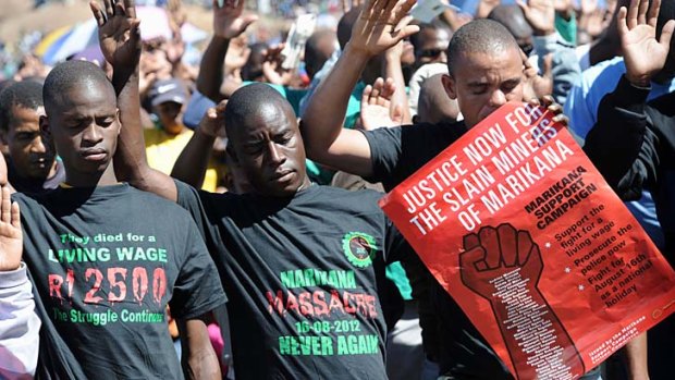 Co-workers of 34 miners shot dead by South African police during a violent wage strike pray during a ceremony to mark the first anniversary of their deaths.