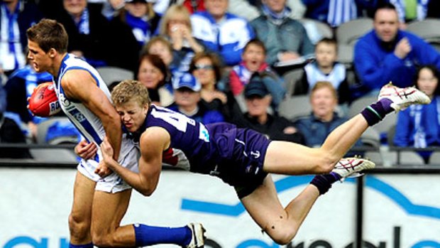 North Melbourne’s Andrew Swallow is caught in a flying tackle by Docker Jesse Crichton.