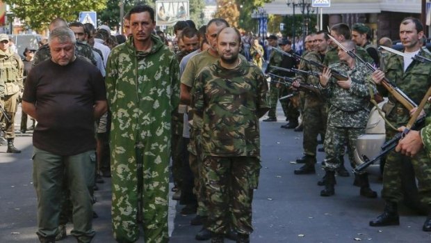 Armed pro-Russian separatists (right) escort a column of Ukrainian prisoners of war across central Donetsk.