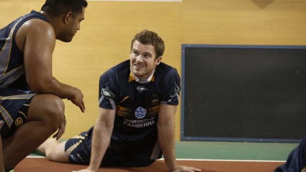 ACT Brumbies player Pat McCabe, centre, chats with a team mate as he warms up before biometric testing in the AIS Indoor Athletics Track.