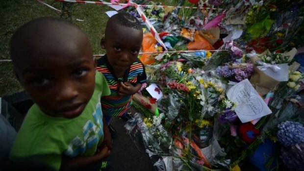 Children stand by a wall of flowers laid by mourners outside Mandela's home in Houghton.