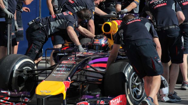 Red Bull mechanics push Vettel's car into the garage.