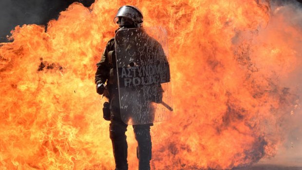 Up in flames ... burning firebombs form a backdrop to a riot officer during a demonstration in Athens on Wednesday.
