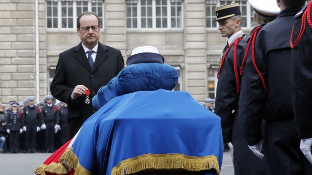 French President Francois Hollande holds the Legion of Honour medal in front of the coffin of French Police officer Clarissa Jean-Philippe during a ceremony to pay tribute to the three police officers killed in the islamist attacks.