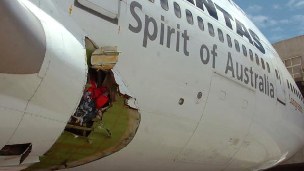 Qantas pilot Captain John Francis Bartles inspects the hole in the fuselage.