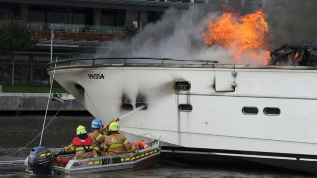 Three men in a tinny: Firefighters extinguish a burning yacht in March last year.
