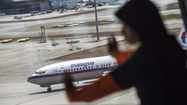 A young girl looks on as a Malaysian Airline aircraft taxis on the tarmac at Kuala Lumpur International Airport.