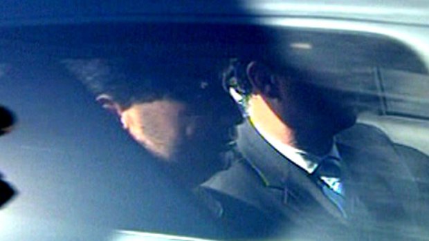 Lloyd Rayney is driven away in a police car after being charged with wilful murder over his wife's 2007 death.
