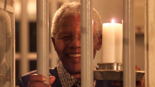 Former South African President Nelson Mandela looks through the bars of his prison cell where he was imprisoned on Robben Island during millennium celebration in Cape Town.