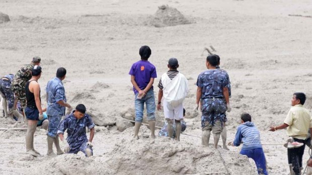 Police and military personnel, aided by civilian volunteers, dig through mud and silt during rescue operations following the flash floods.