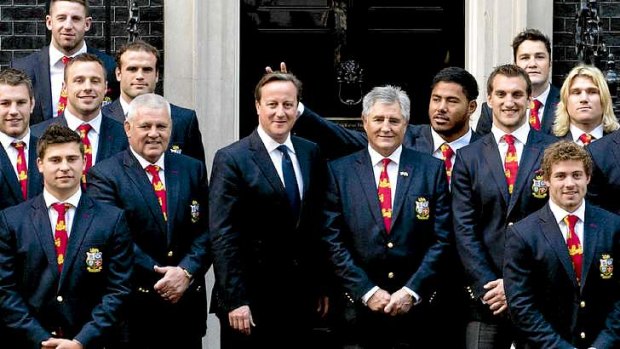 British and Irish Lions rugby player Manu Tuilagi gestures behind the head of British Prime Minister David Cameron.