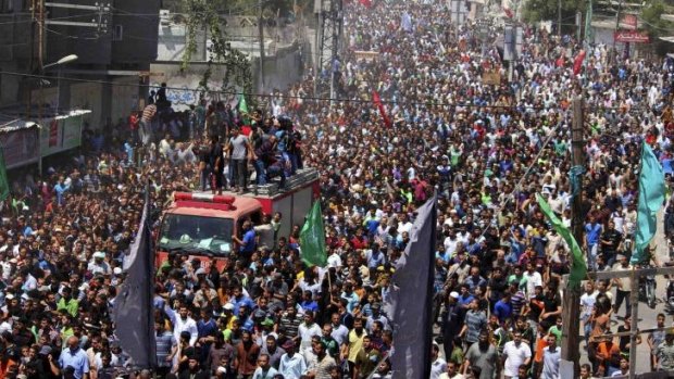 Tens of thousands of Palestinians march in the funeral of three slain Hamas commanders in Rafah in the southern Gaza Strip.
