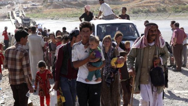 Displaced people from the minority Yazidi sect, fleeing Islamic State militants in the Iraqi town of Sinjar, re-enter Iraq from Syria at the Iraqi-Syrian border crossing in Fishkhabour. Some have scrambled onto military helicopters on aid missions.