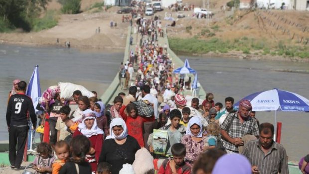 Displaced Iraqis from the Yazidi community cross the Syrian-Iraqi border.