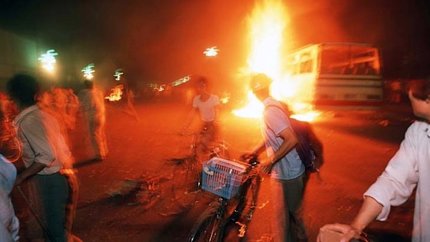 As buses and vehicles burn, pro-democracy demonstrators retreat down Changan Avenue as soldiers advance towards the square.