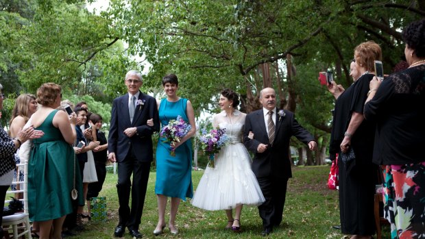 Mick Kyriacou (R) walks his daughter Joy Kyriacou down the aisle, alongside Joy's partner and her father, at her commitment ceremony.