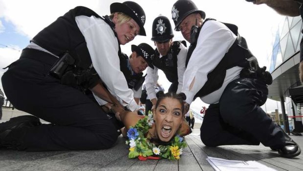 A Femen activist is detained during a protest against what they called "bloody Islamist regimes" taking part in the London Olympics.