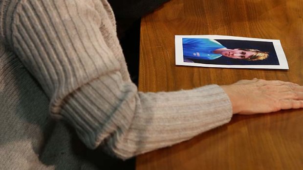 A picture of Thomas Kelly lies by the hand of his distraught mother during today's briefing.