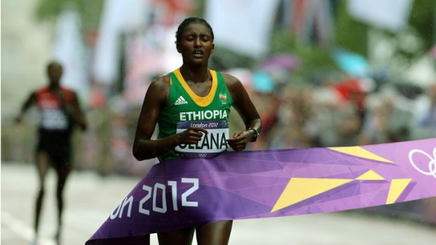 An exhausted Tiki Gelana of Ethiopia crosses the finish line to win the women's marathon.